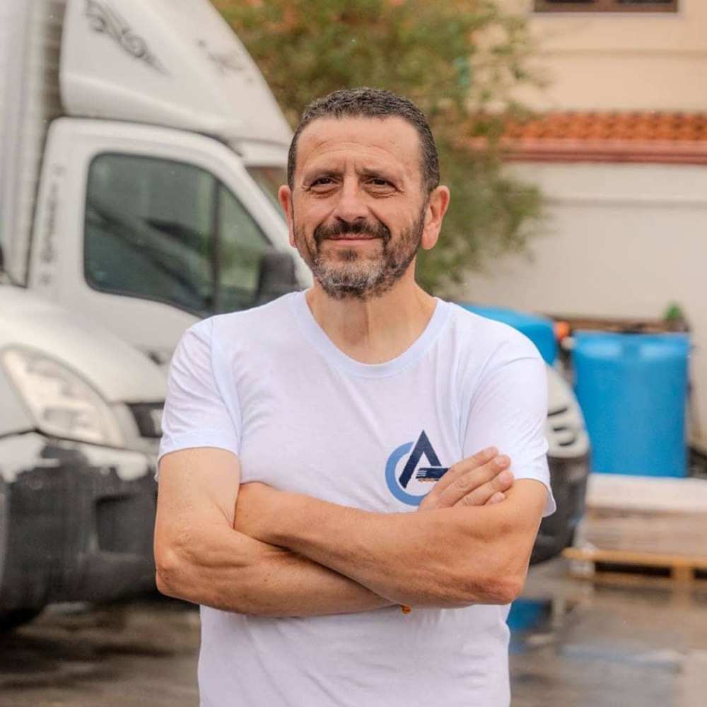 Andrea Cacciapuoti a braccia conserte davanti ai mezzi dell'impresa
