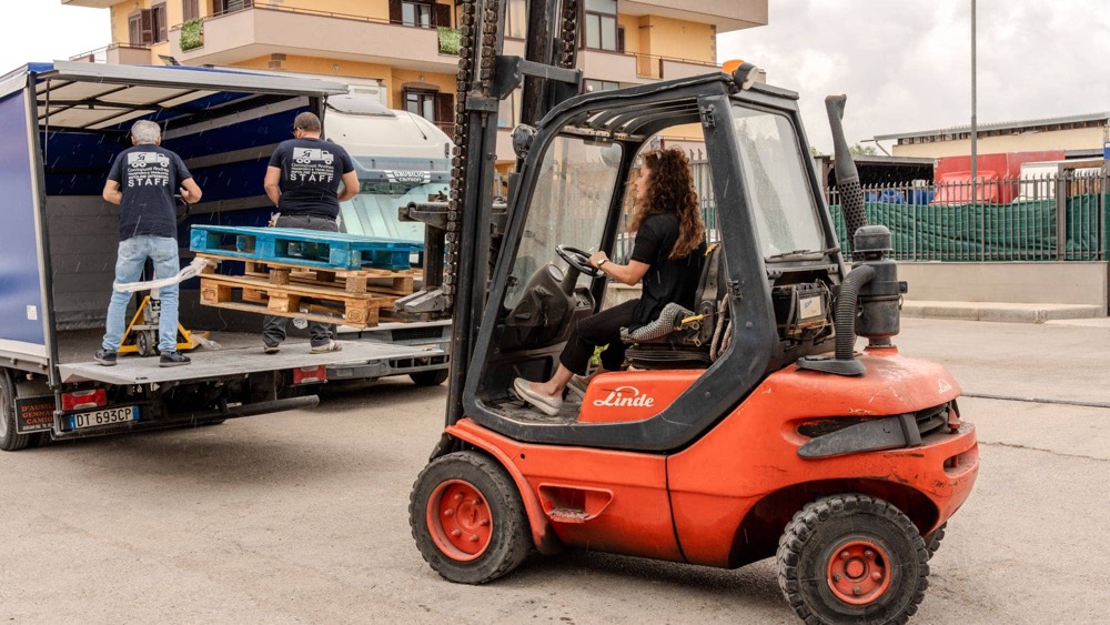 Il muletto affianca il camion mentre due operatori sistemano il carico