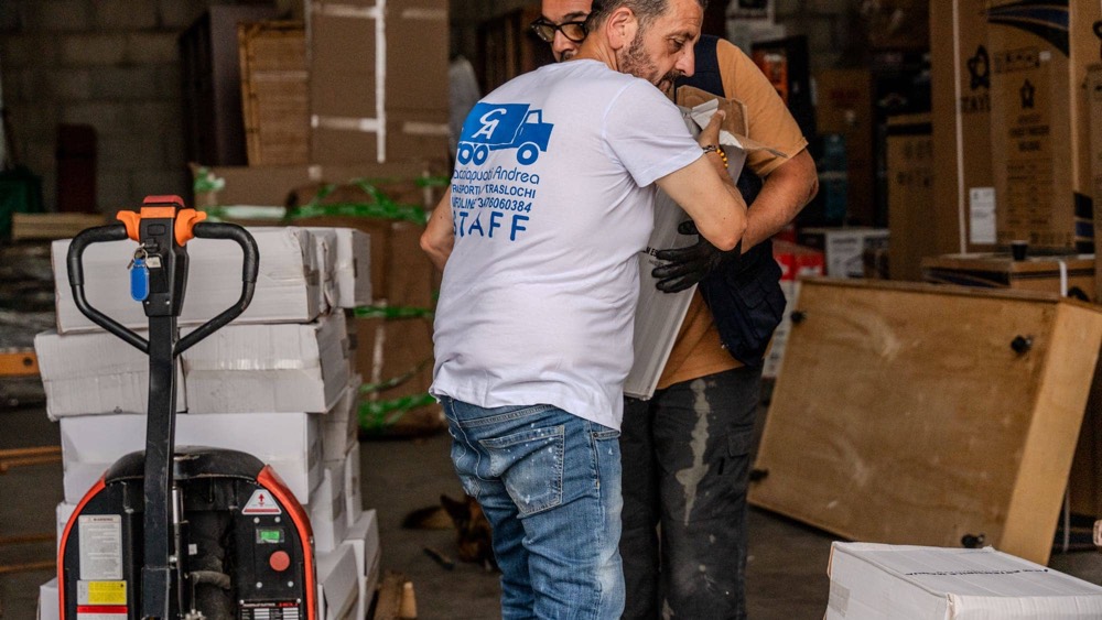 Due operatori si passano un imballo dentro il deposito