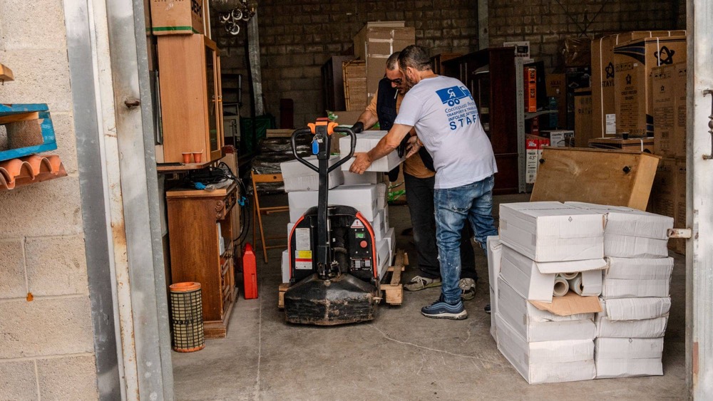 Un operatore manovra il transpallet fra le corsie del deposito